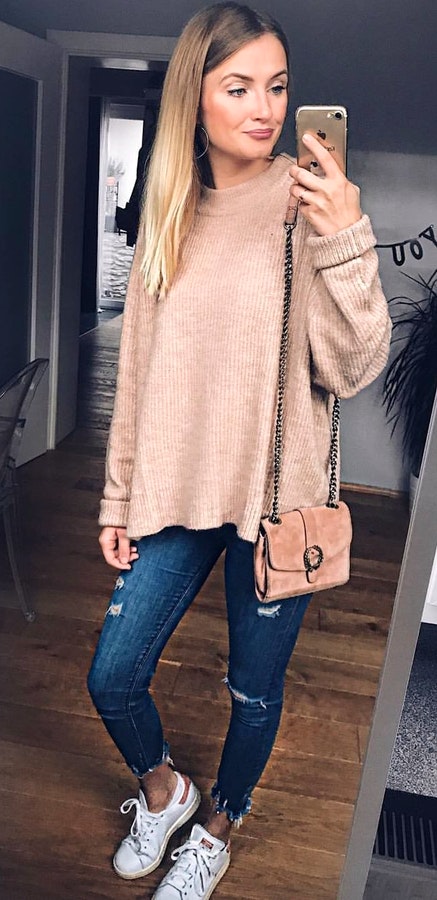 Women's beige sweater, blue denim jeans, and white lace-up shoes.