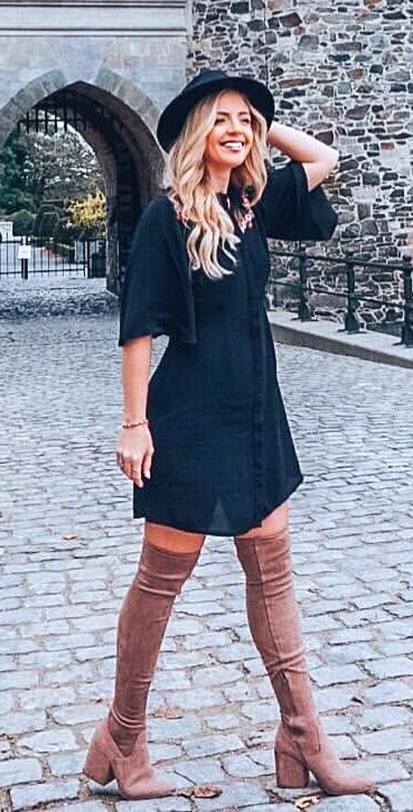 Women's black elbow-sleeved dress and brown leather knee-high chunky heeled boots, and black hat.