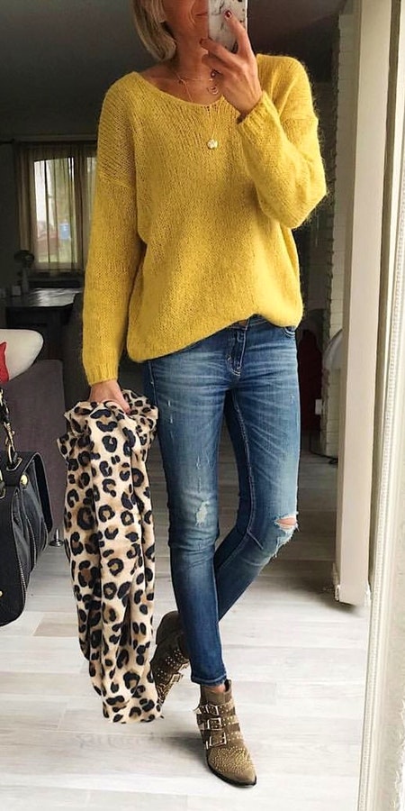 Women's yellow sweater and distressed washed blue jeans.