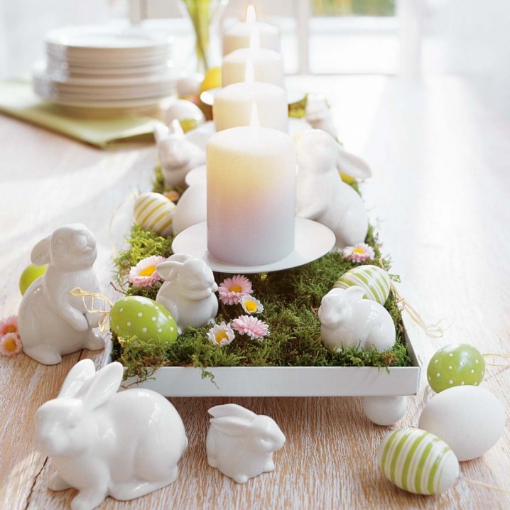 Candle centerpiece features grass, eggs and bunny decorations.
